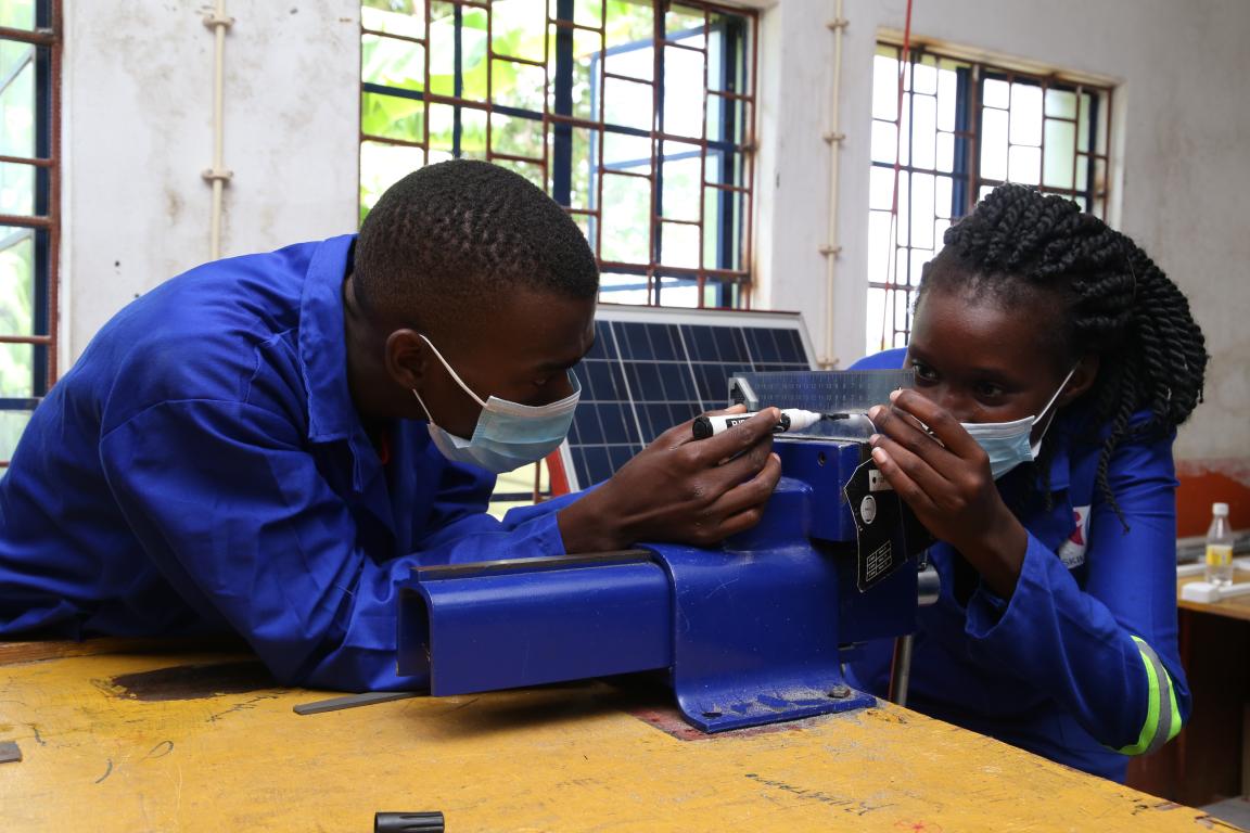 Two trainees performing precision work on a device.
