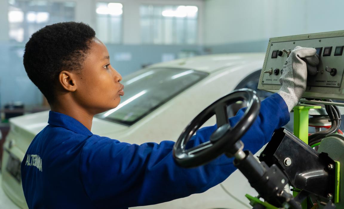 A motor vehicle apprentice works on a diagnostic device in the car repair shop.