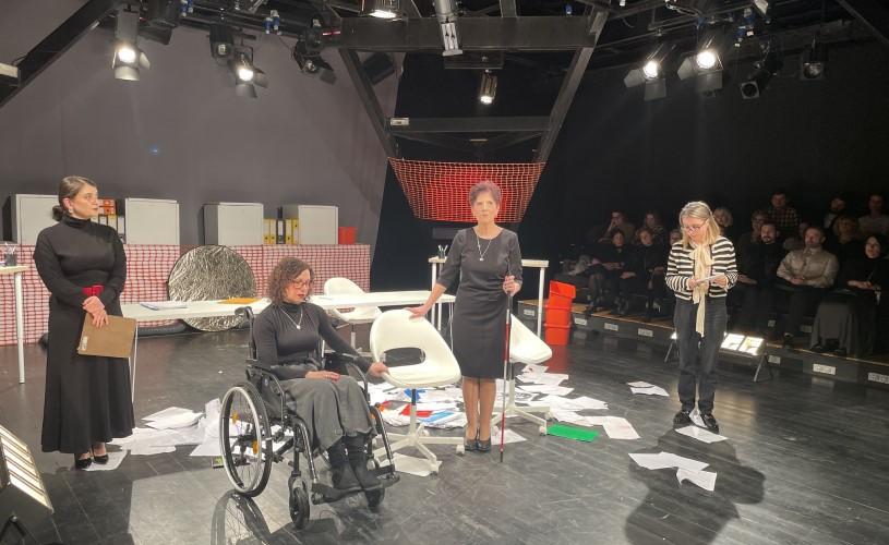 A group of people are standing around a woman in a wheelchair and chatting amiably with each other.