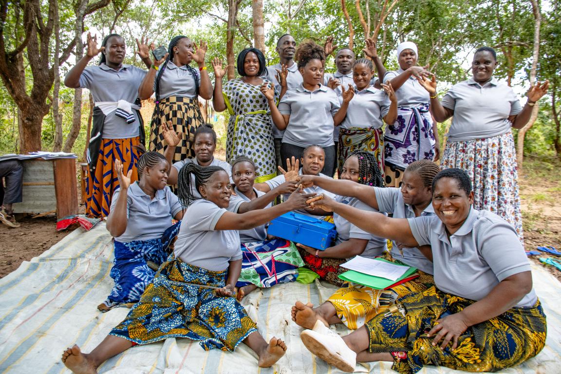 Women from a village savings group sit and stand together for a photo.