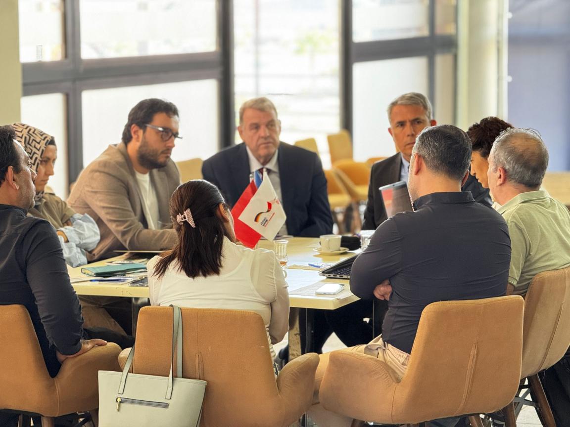 Menschen sitzen an einem runden Tisch zusammen.