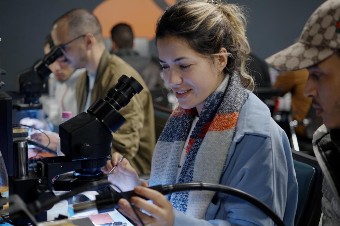 Young people are working on microscopes during a training session.