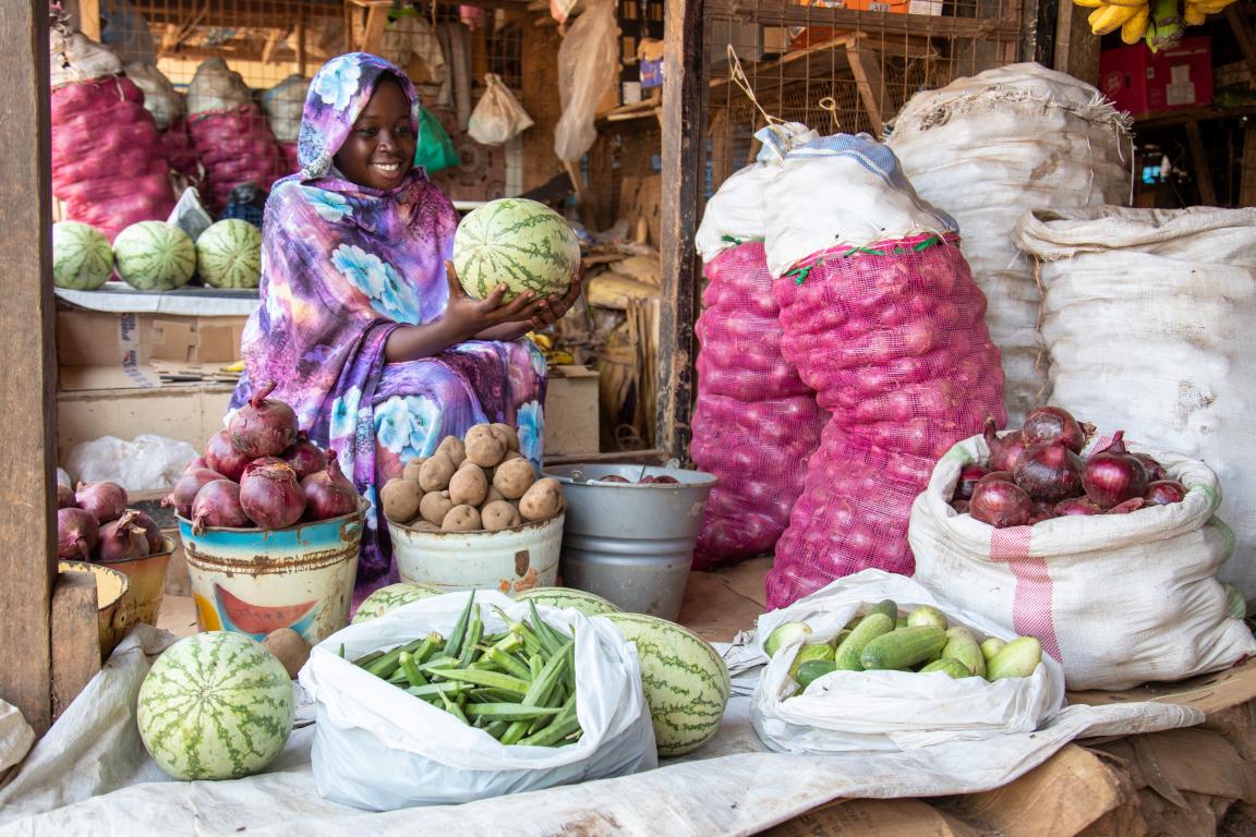 Woman sitting relaxed on a chair surrounded by vegetables.