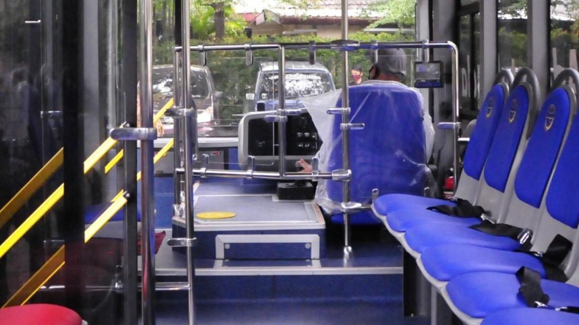 Innenansicht eines modernen Linienbusses in Indonesien: blaue und rote Sitze mit Gurten, breiten Gängen und barrierefreien Vorrichtungen für die Fahrgäste.