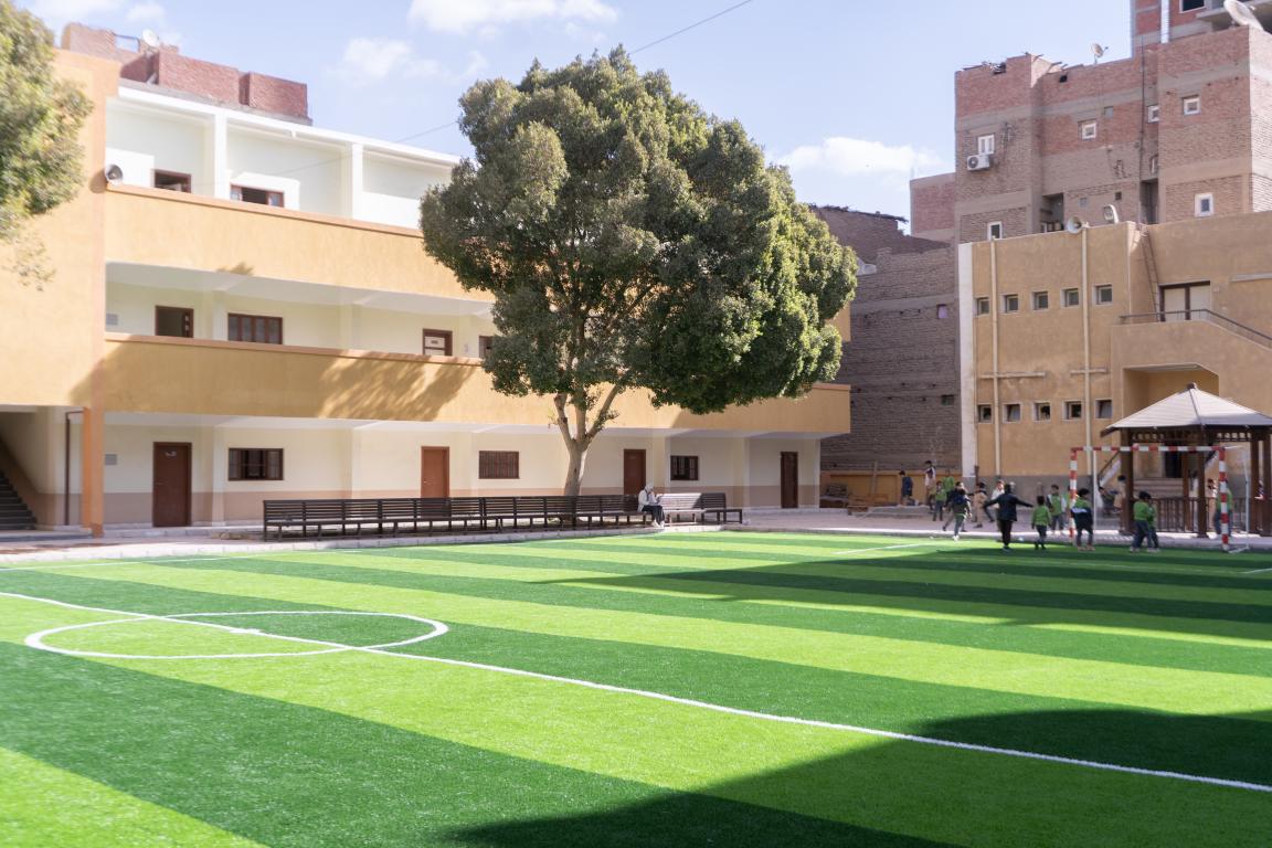 Refurbished school with football pitch and children playing.