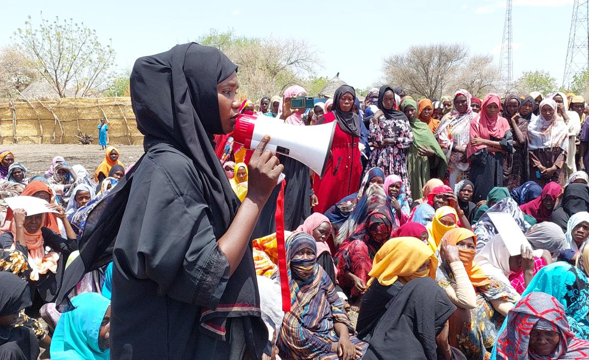 Women in Sudan listen to a woman with a megaphone.