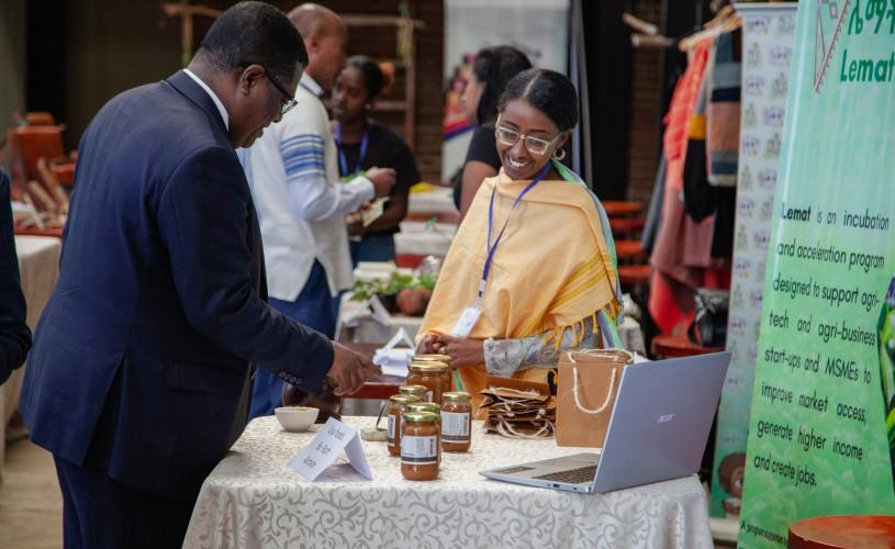 : A woman entrepreneur showcasing her honey products to the State Minister of Industry at the Startup Ecosystem Festival in Ethiopia.