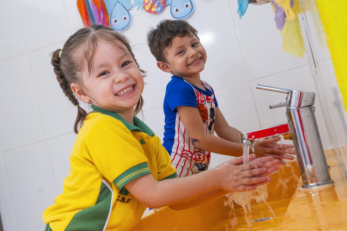 Children wash and smile at the camera.