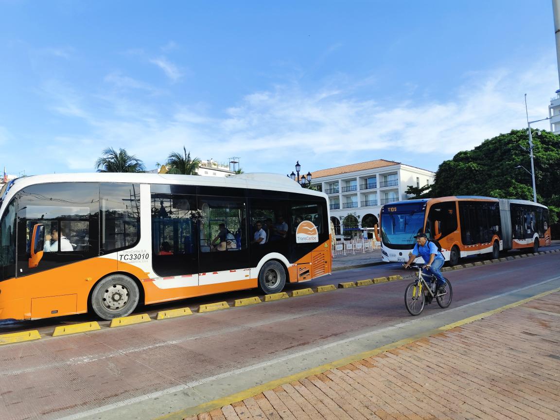 Nachhaltiger Stadtverkehr in Cartagena, Kolumbien: Nahverkehrsbusse fahren auf einer getrennten Spur neben einem Fahrradfahrer.