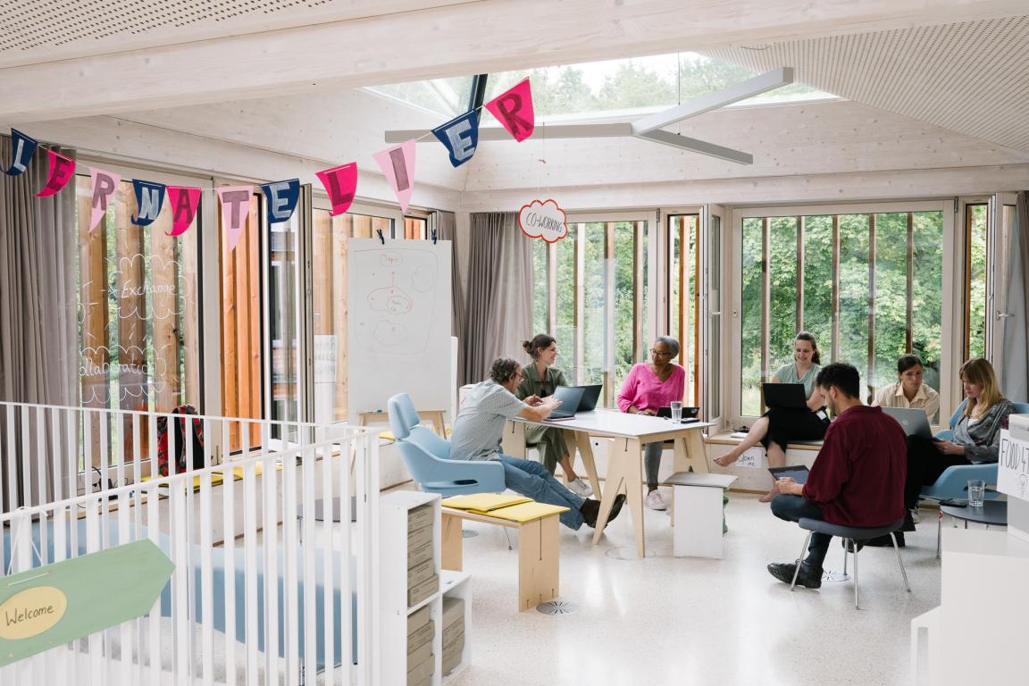 Menschen sitzen im Lernatelier an Laptops.