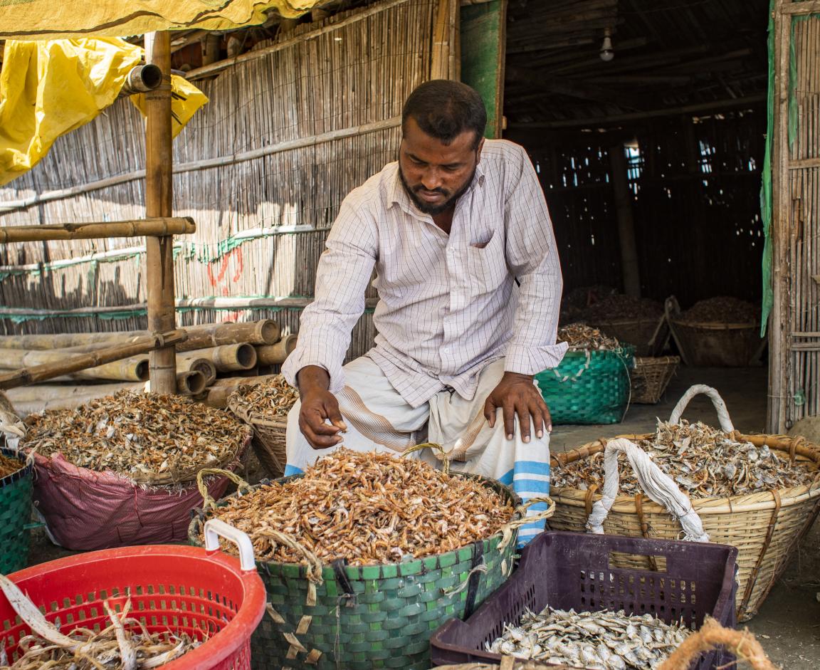 A man selling dried fish at a bazaar.