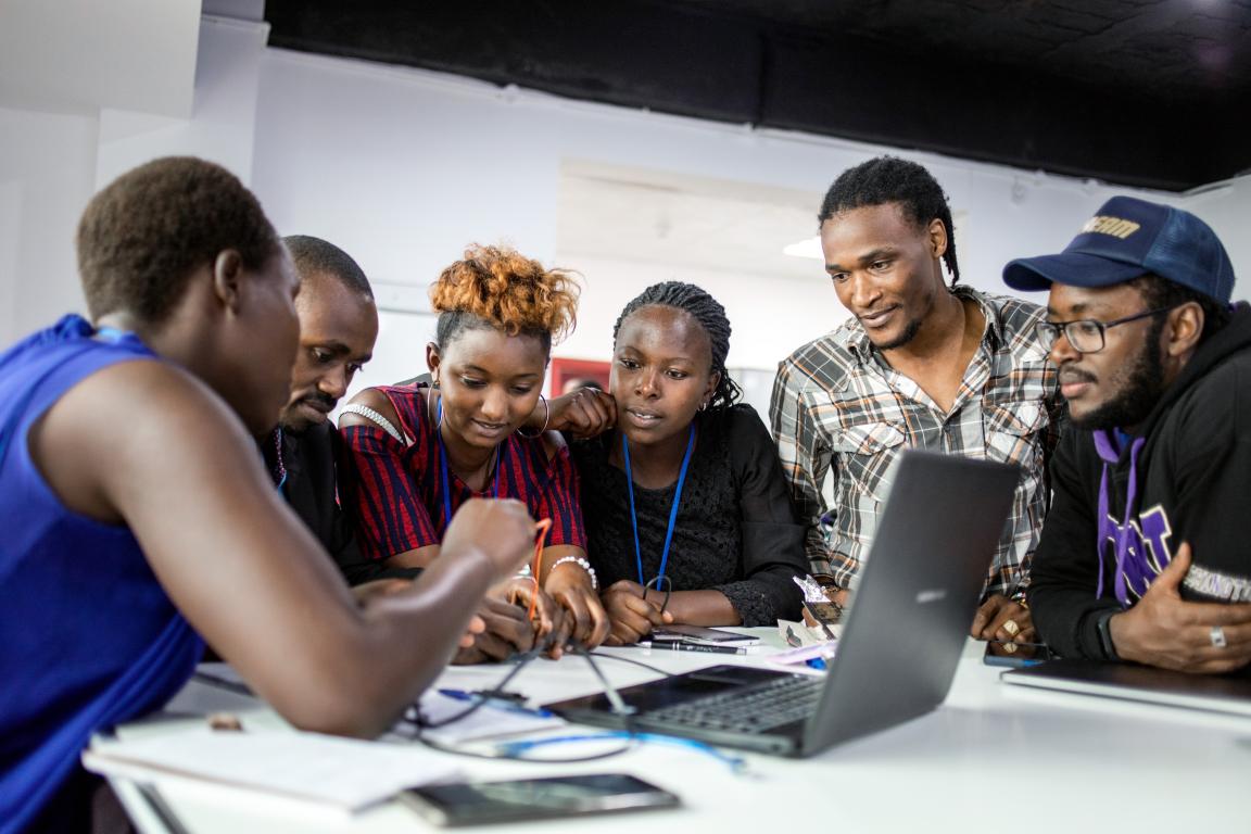 Six participants on a training course seated around a laptop.