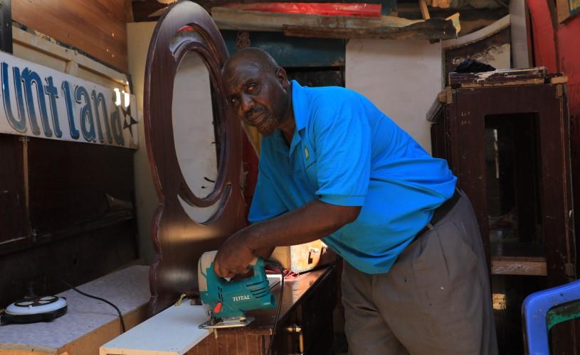 A man using a jigsaw to craft furniture during vocational skills training.