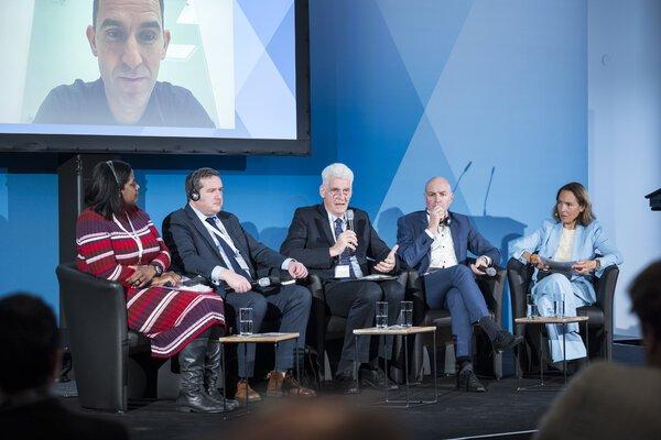 Five people seated on stage at the annual congress of the National Forum against Homelessness. A man is visible on a video screen behind them.