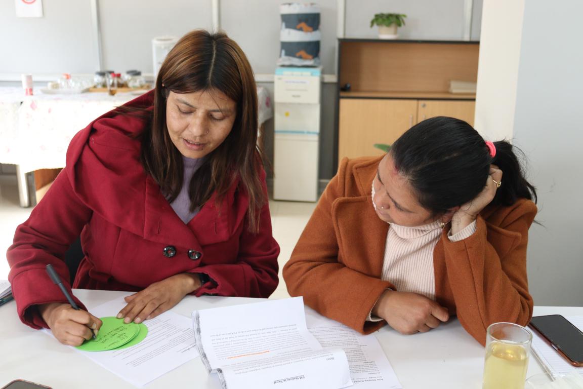 Zwei Frauen arbeiten in einem Kurs zur Konfliktbearbeitung zusammen. Eine Frau schreibt Stichpunkte auf.