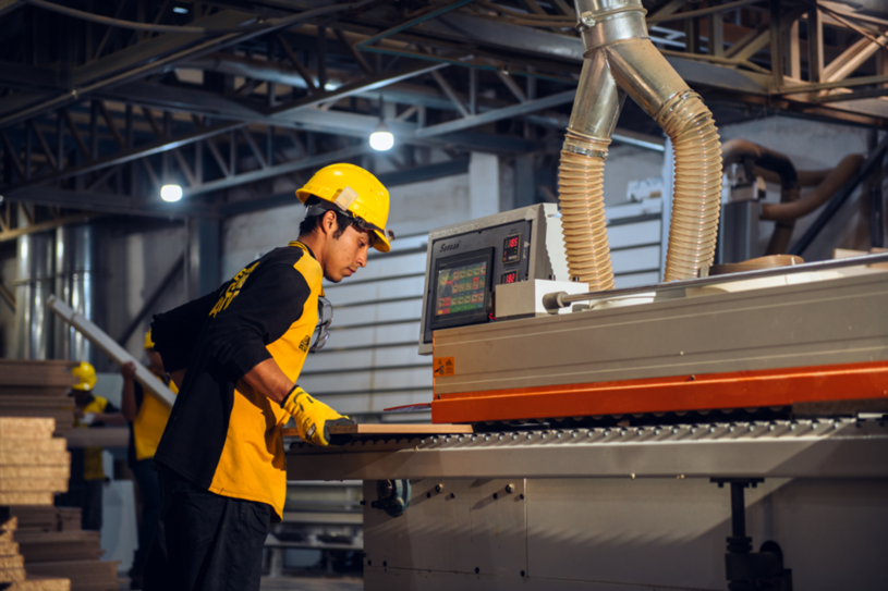 An employee of a company using a woodworking machine.
