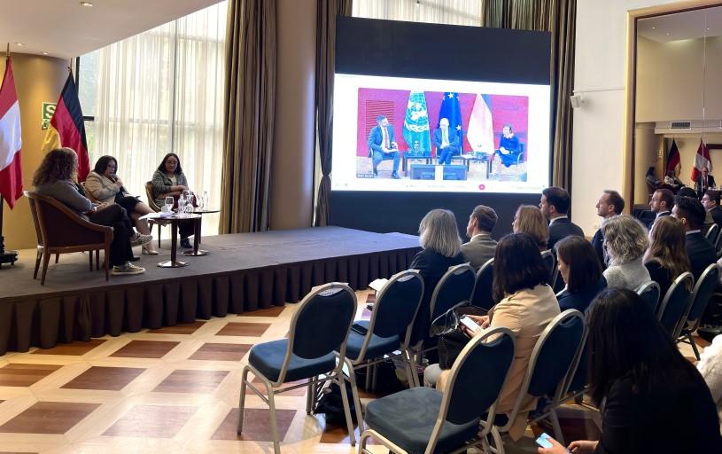 Encuentro entre el Perú y Alemania: Funcionarios y funcionarias en una sala en el Perú con una pantalla que muestra funcionarios y funcionarias en Alemania.