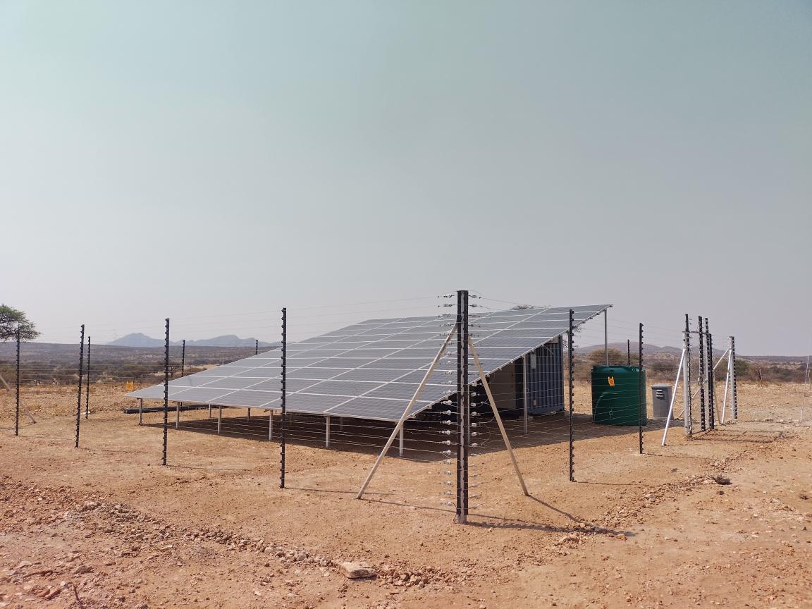 A solar power plant surrounded by a fence in a dry landscape.