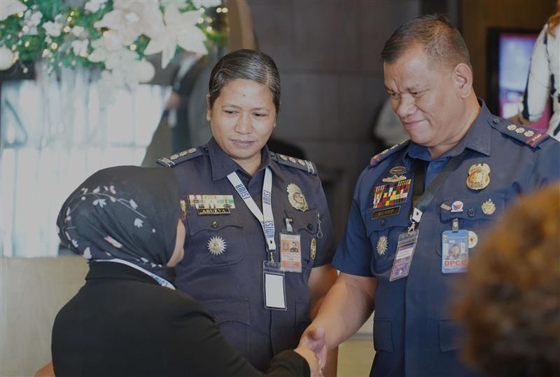 Eine uniformierte Frau und ein Mann danken einer Frau mit Kopftuch per Handschlag.