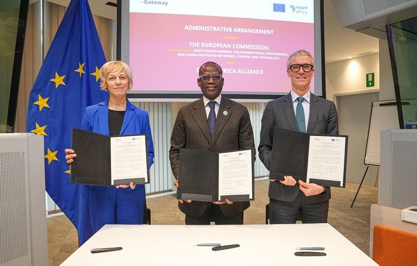 Three people – Lacina Koné, Koen Doens and Renate Nikolay – hold signed documents up to the camera.