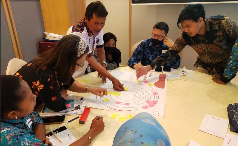 Participants of an anticorruption training in Sorong discuss stakeholder mapping using coloured notes during a group exercise.