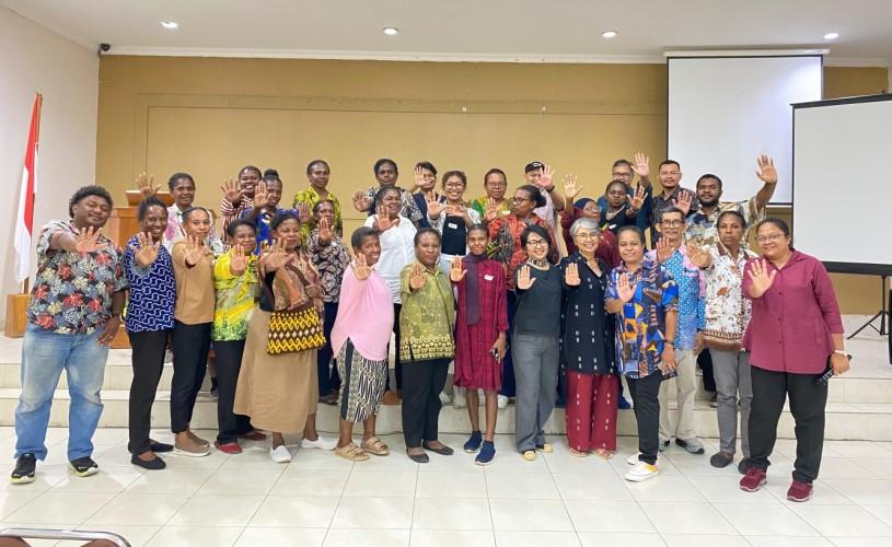 Gruppenfoto von Teilnehmer*innen und Trainer*innen einer Schulung zur Korruptionsbekämpfung für indigene Frauen in Indonesien, die alle lächeln und die Hände heben.