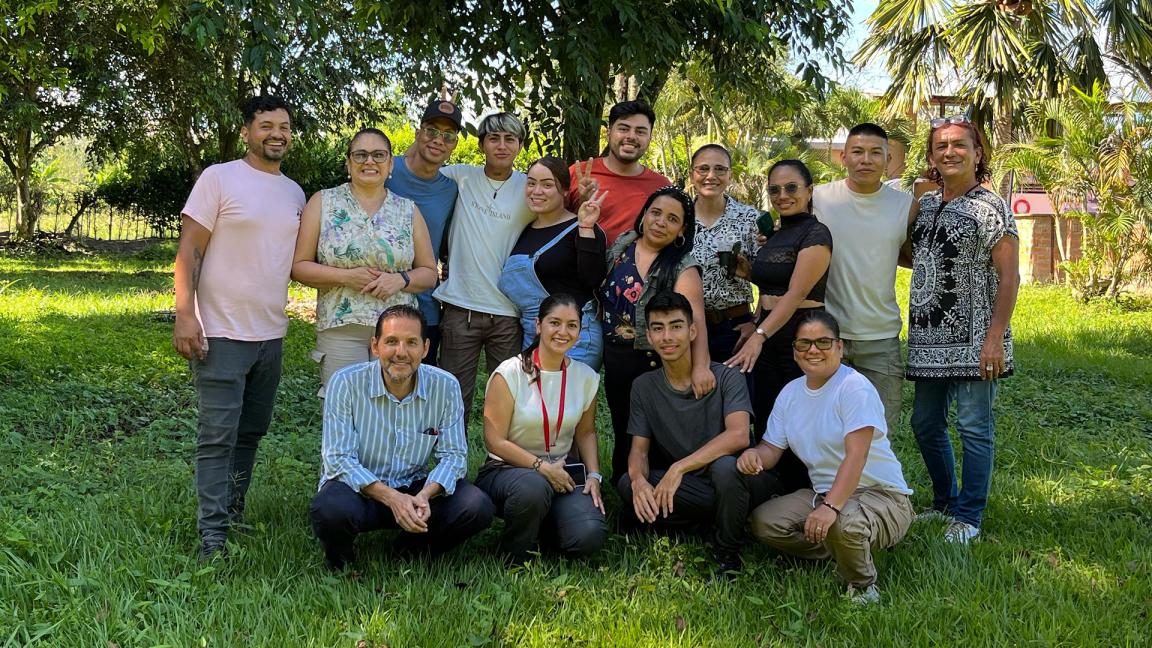 People are standing together in a green setting for a photo at an event.