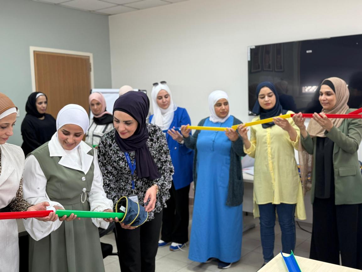 Group of women in a room holding colorful rods and interacting with each other.