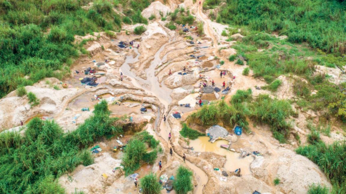 A degraded landscape with several unrehabilitated mining pits and small groups of miners surrounded by vegetation.