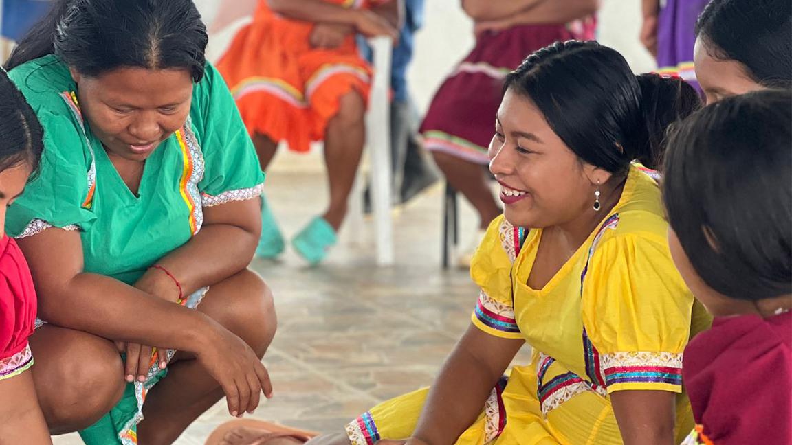 Mujeres indígenas sentadas juntas en un evento.