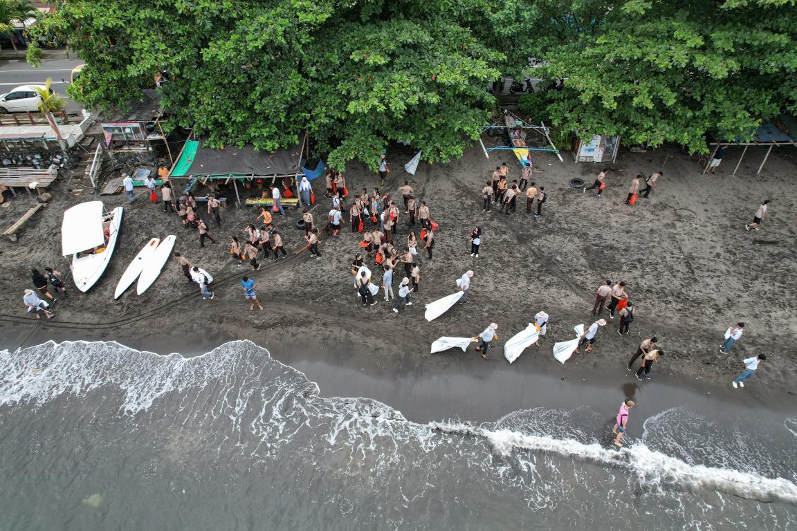 Aerial view of a beach where people are collecting litter.