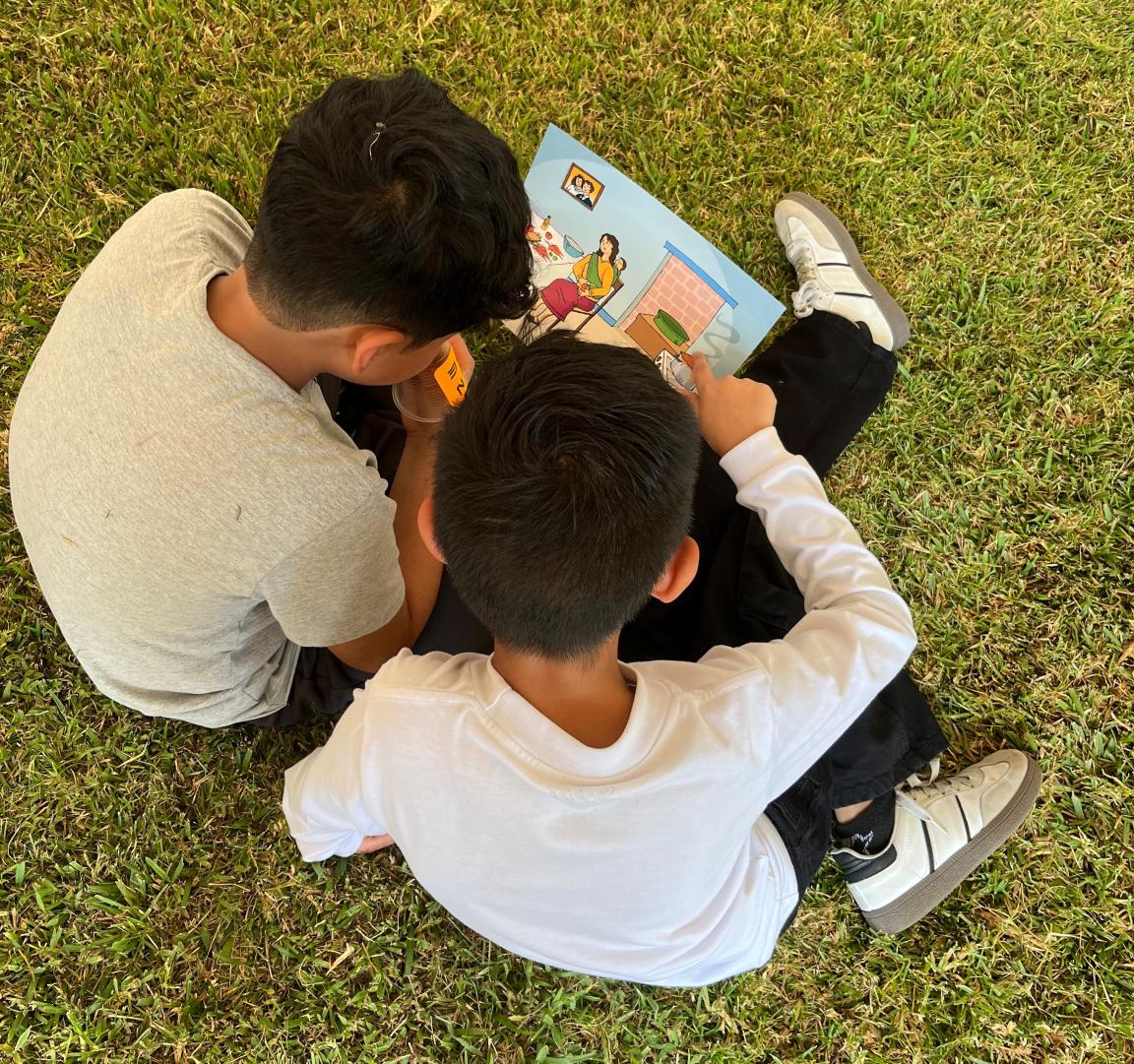Dos niños leen juntos un libro y aprenden de forma lúdica sobre la prevención de la violencia contra las mujeres. 