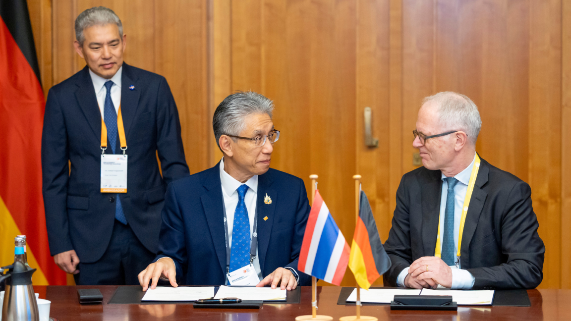 BMWK-Staatssekretär Udo Philipp und der Berater des thailändischen Energieministers Samerjai Suksumek sitzen an einem Tisch und unterschreiben den Energiedialog.