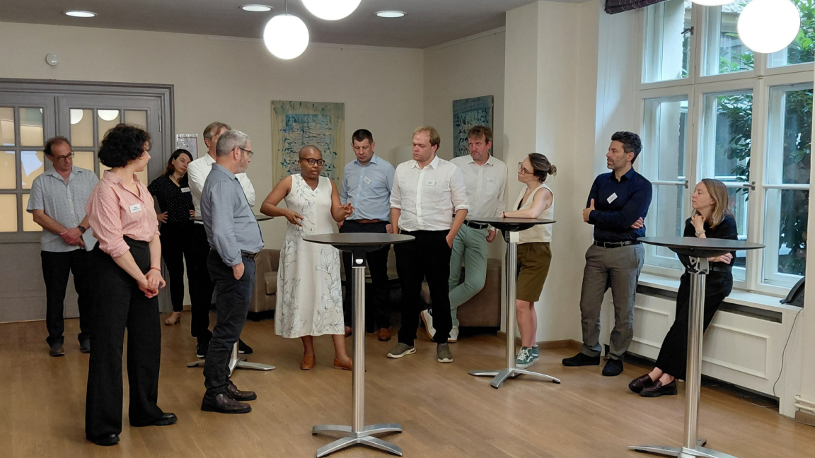 Zwölf Personen stehen um Stehtische herum und unterhalten sich beim Expertendialog im Juni 2026.