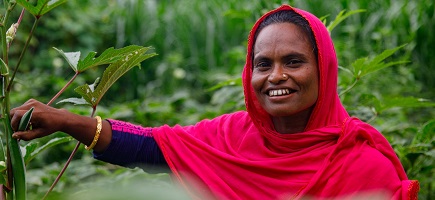 Eine Frau mit rotem Kopftuch vor einem grünen Hintergrund blickt in die Kamera.