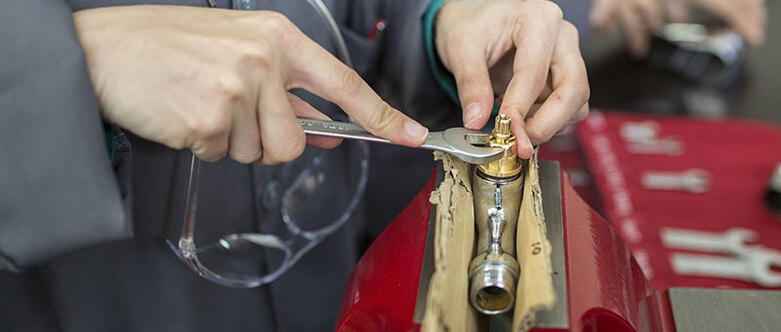Eine Person repariert etwas mit einem Schraubenschlüssel