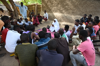 Eine Gruppe schart sich um eine Frau, die etwas erklärt. Alle sitzen auf dem Boden. © GIZ / Abdrahamane Karimou Issa 