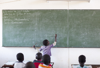 Ein Kind in einem Klassenraum schreibt etwas an die Tafel.