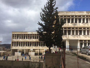 Ansicht vom Schulhof auf eine zur Sanierung/Rehabilitierung vorgesehenen Schule. Im Doppelschichtbetrieb werden morgens libanesische und nachmittags syrische Schüler unterrichtet. El Minieh-Dennie, Nordlibanon (März 2016) © GIZ