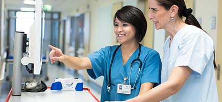Zwei Krankenschwestern sehen auf einen Monitor.