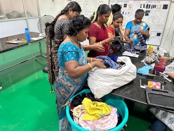 Frauen sortieren Post-Verbraucher-Textilabfälle nach tragbaren und nicht tragbaren Materialien.  (© GIZ Indien / Isha Sharma)