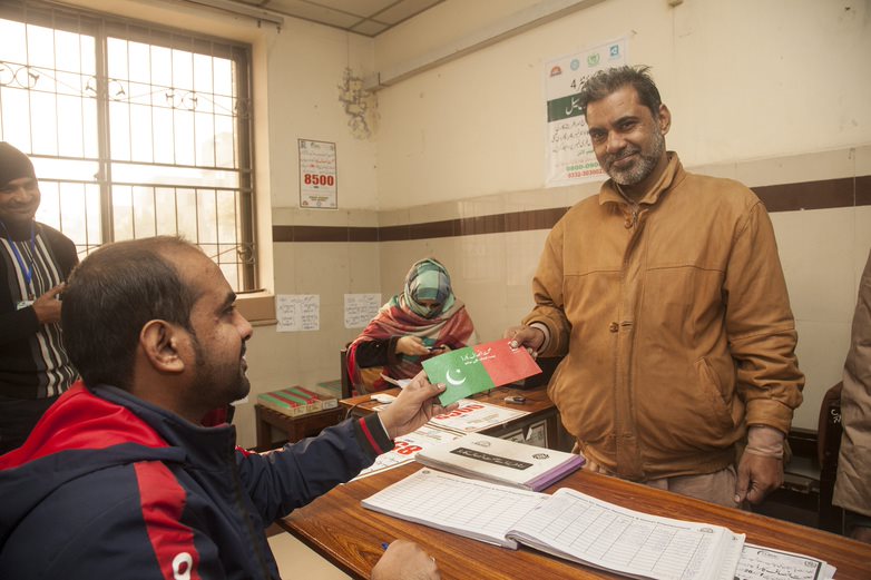 Ein Leistungsempfänger erhält eine Krankenversicherungskarte im Anmeldezentrum in Lahore, Punjab. 