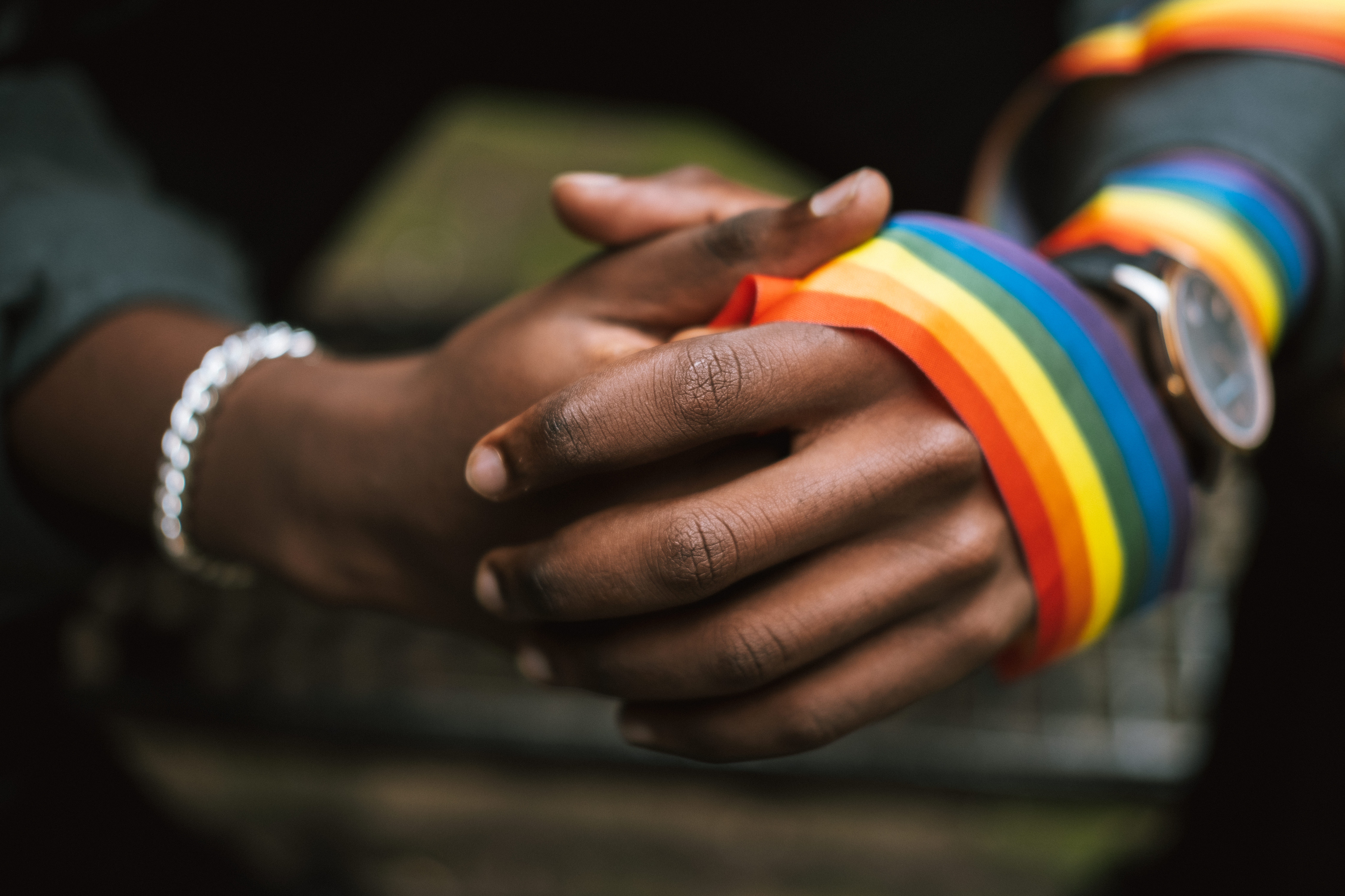 Eine Person trägt regenbogenfarbene LSBTI*-Bänder an ihrer Hand und ihrem Arm. ©GIZ/Anete Lusina (https://www.pexels.com/de-de/foto/mann-strasse-schild-gesichtslos-5721294/)