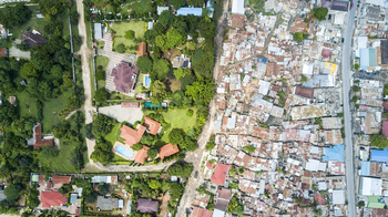 Das Foto ist in Dar es Salaam, Tansania, entstanden. Es verdeutlicht die Ungleichheiten zwischen den Bewohner*innen des exklusiven und wohlhabenden Randbezirks Masaki und den Menschen, die im ärmeren Randbezirk Msasani leben. Die meisten Expats und wohlhabenden Menschen leben in Masaki oder Oyster Bay, den ehemals „europäischen Gebieten“, die den Kolonialherren vorbehalten waren.