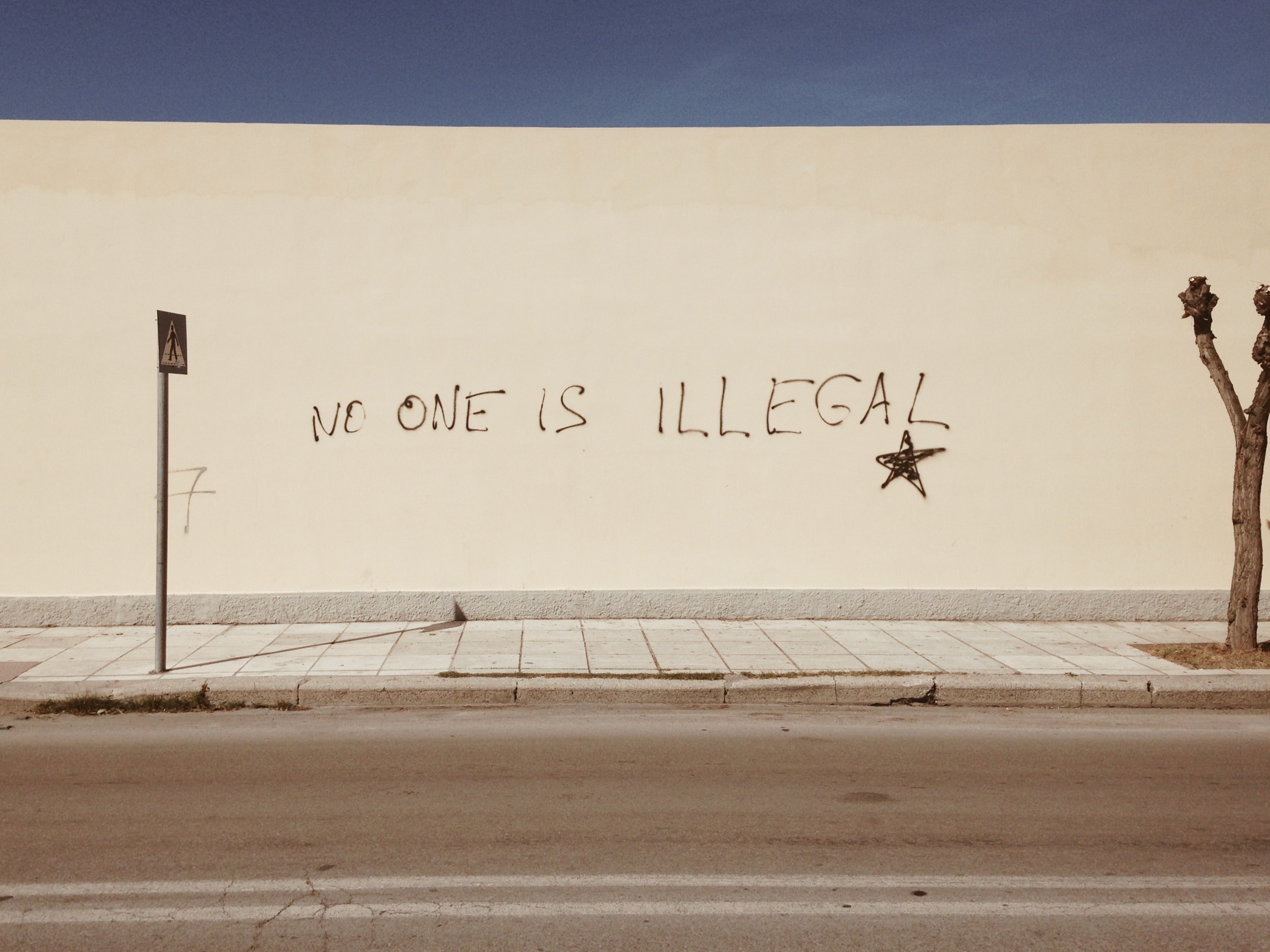 Graffiti mit dem Schriftzug „No one is illegal“ an einer Straßenwand. © ©GIZ/Miko Guziuk (https://unsplash.com/photos/JxzaDHkcOSo)