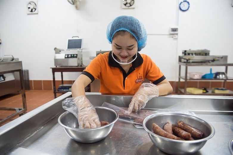 Eine kambodschanische Angestellte arbeitet sorgfältig an der Wurstproduktion für das Wurstunternehmen Ly Theang Seng.
