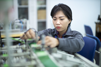 Eine Schülerin arbeitet in einer vietnamesischen Berufsschule an einem technischen Gerät. © GIZ/Thomas Imo