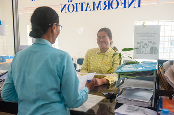 Eine Frau steht an einem Bürgerservice-Schalter und erhält Dokumente. Copyright: GIZ/Conor Wall