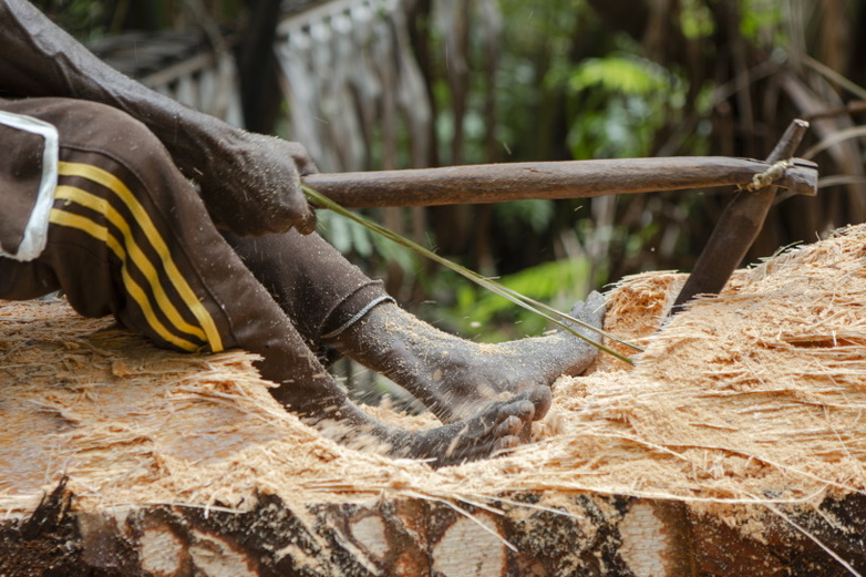 Einwohner*innen von Papua mahlen Sago mit einem traditionellen Werkzeug.