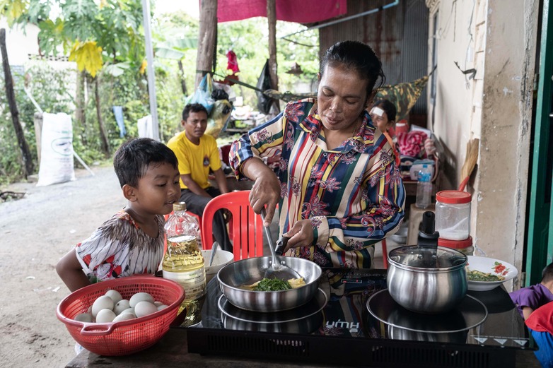 Eine Frau kocht mit ihrem neuen elektrischen Kochherd, während ihr Sohn zuschaut. © GIZ/ Enric Catala Contreras (RVO)